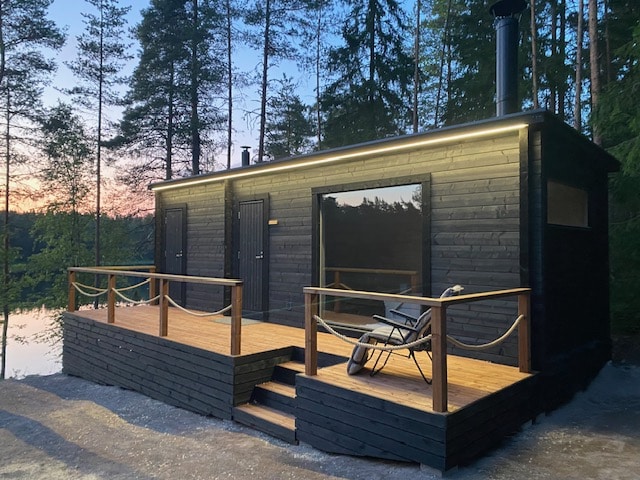 Hirsinen saunamökki terassilla järven rannalla