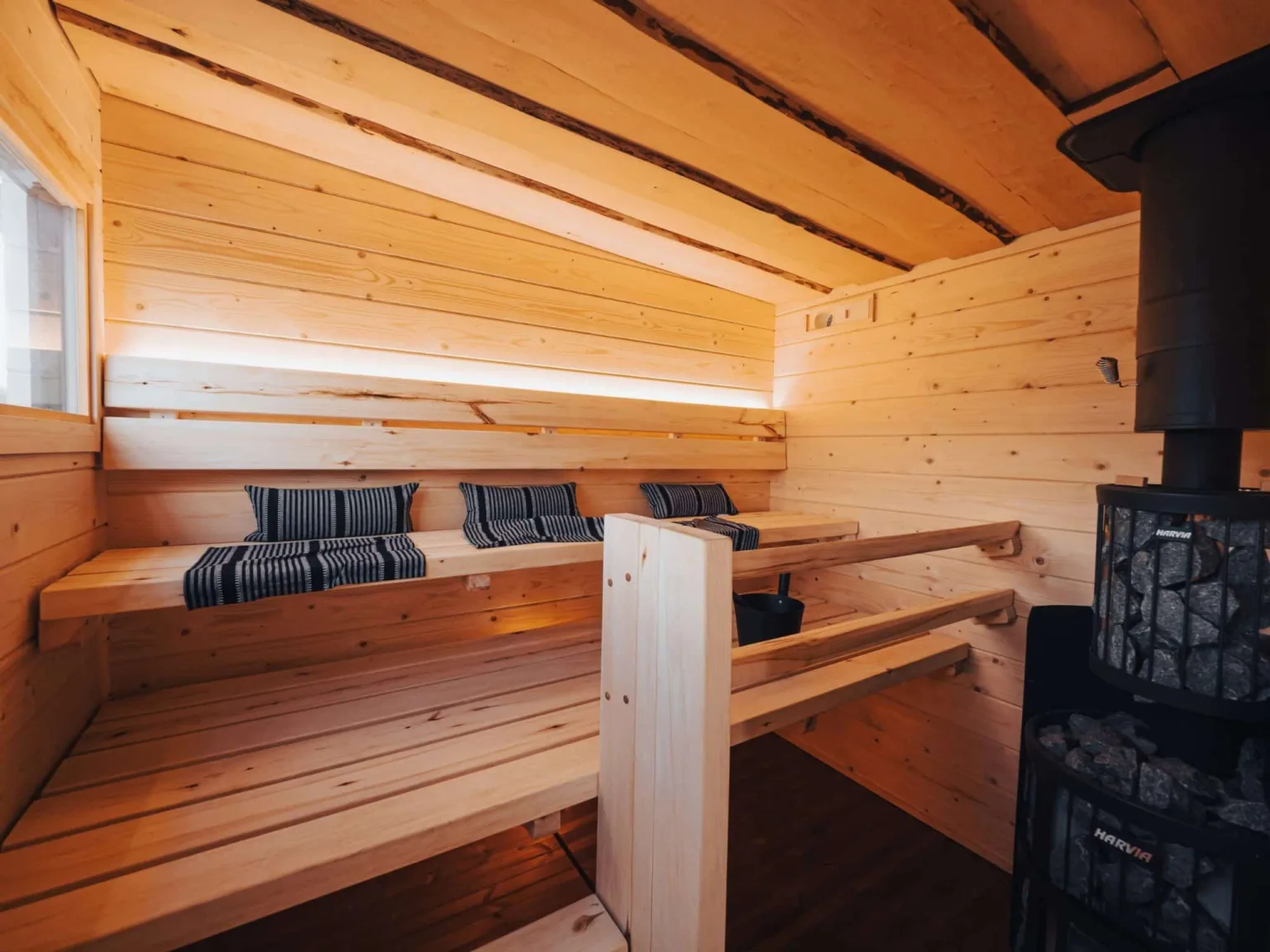 Tervaksen vaalea hirsisauna mustalla kiukaalla.
